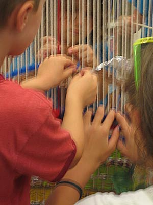 Children's hands weaving together on the Story Loom