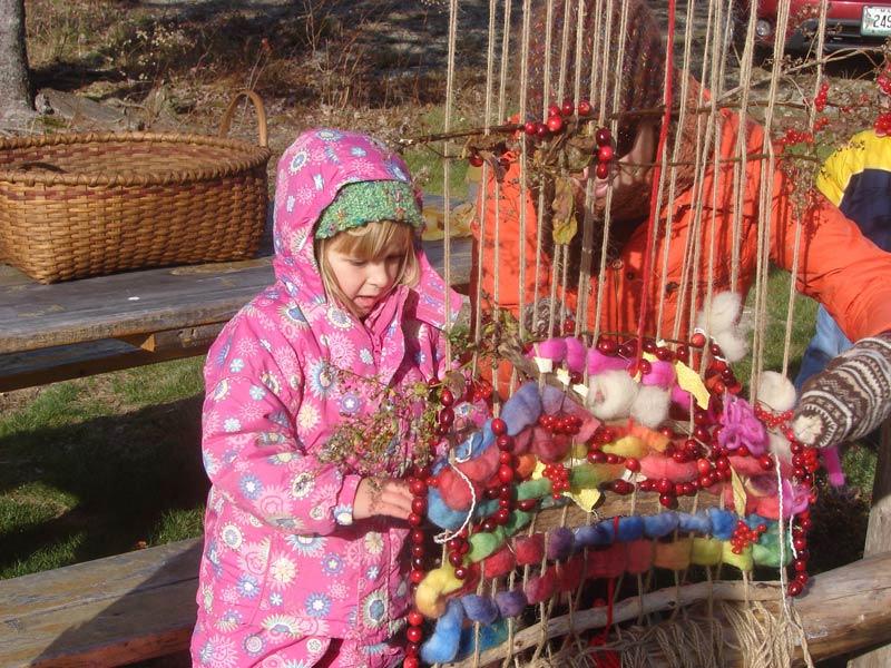 A girl braves the cold to weave food for the birds on the EarthLoom